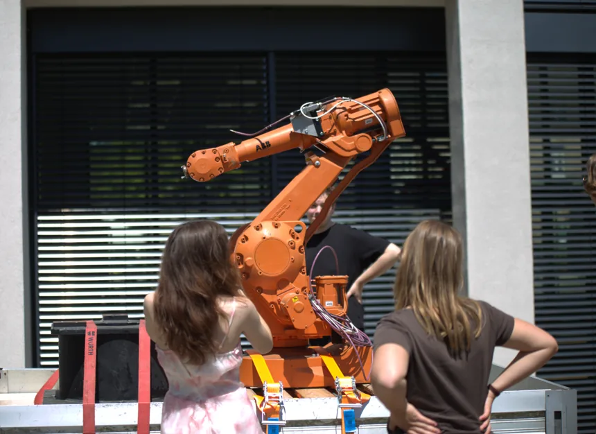 Zwei Personen vor einem orangefarbenen Industrieroboter auf der IoT-Party